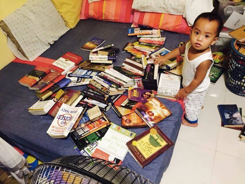 My son Miggy playing with my disorganized book collections